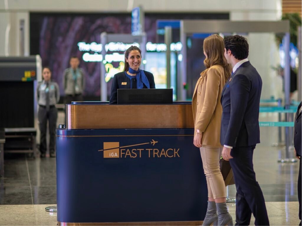 Travelers being assisted at a "Fast Track" airport counter by staff