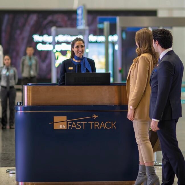 Travelers being assisted at a "Fast Track" airport counter by staff