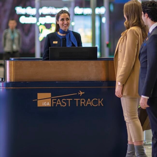 Travelers being assisted at a "Fast Track" airport counter by staff