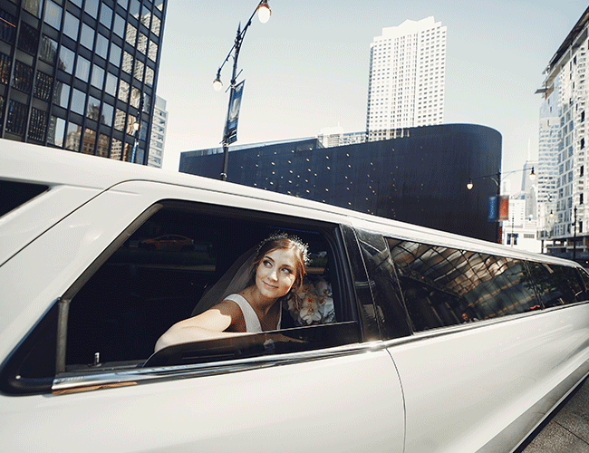 A happy woman in a white dress smiles from the window of a luxury stretch limousine, booked for a special event like a wedding or prom in Istanbul.