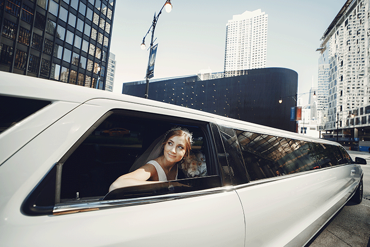 A happy woman in a white dress smiles from the window of a luxury stretch limousine, booked for a special event like a wedding or prom in Istanbul.