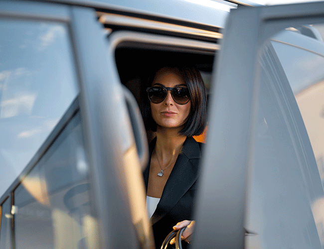 A stylish female passenger getting out of a luxury Limousine Plus van, arriving at her destination in Istanbul.
