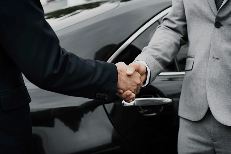 Two businessmen shaking hands in front of a luxury vehicle, symbolizing a trusted B2B transportation partnership with Limousine Plus in Istanbul.