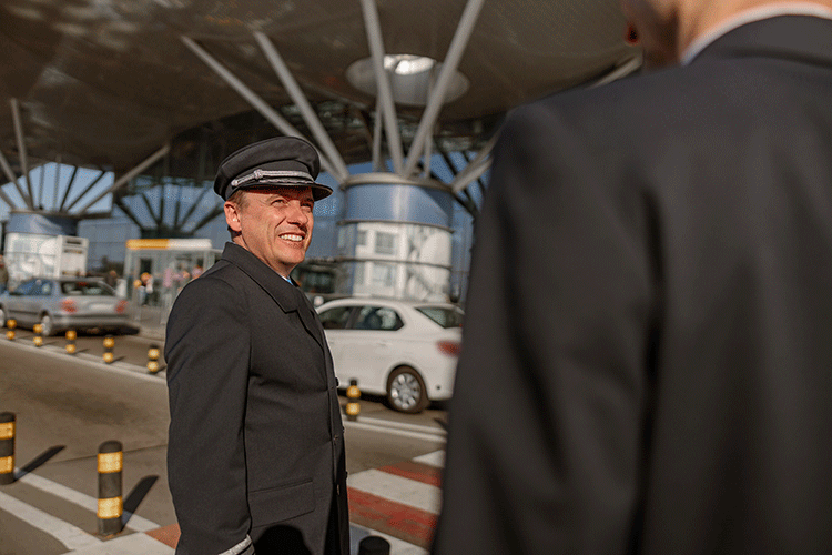 Friendly Limousine Plus chauffeur in uniform welcoming a passenger at Istanbul Airport for a private transfer.